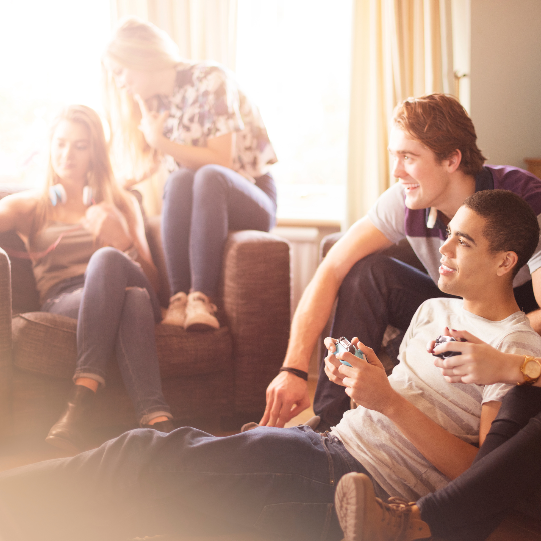 Junge Leute entspannen, reden auf Deutsch und spielen Videospiele in einer Wohngemeinschaft