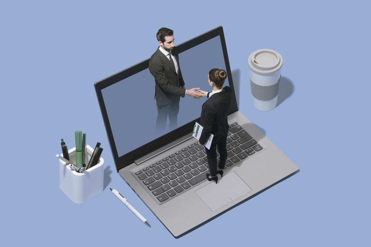 Zwei Geschäftsleute, die sich in einem Laptop-Bildschirm die Hand geben
